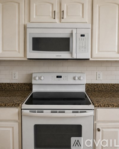 A white microwave oven is mounted above a white stove in a kitchen.