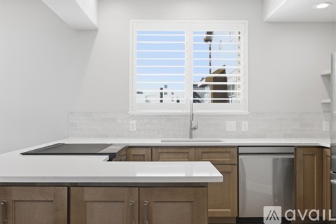 A kitchen with wooden cabinets and a window with blinds.