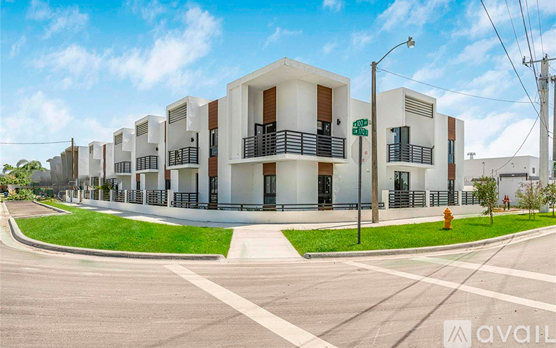 A street view of a residential area with modern buildings and a clear sky.