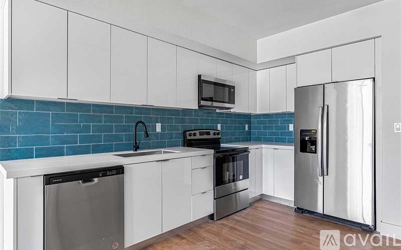 A kitchen with white cabinets and a blue tile backsplash.