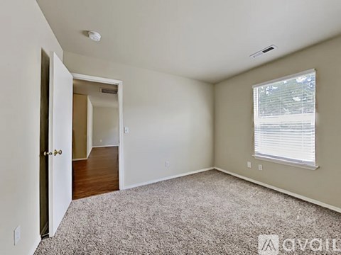 A living room with a carpet floor and a window with blinds.