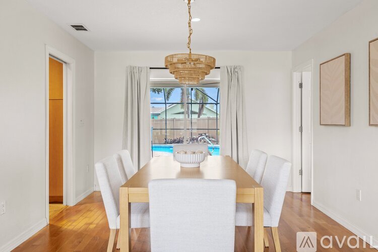A dining room with a wooden table and white chairs.