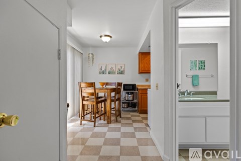 A kitchen with a checkered floor and a dining table with chairs.