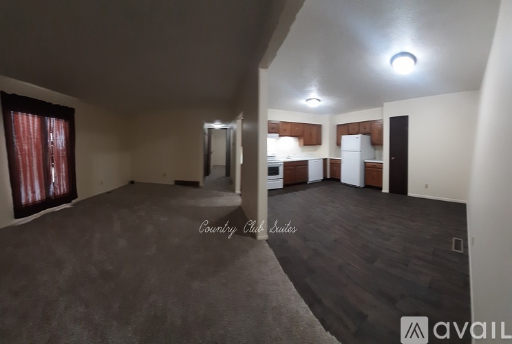 A spacious room with a carpeted floor and a large window with red curtains.