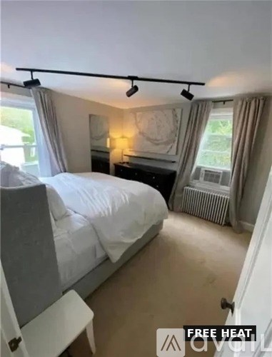 A bedroom with a bed, nightstand, and window.