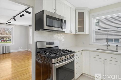 A kitchen with a black microwave above a stove and white cabinets.