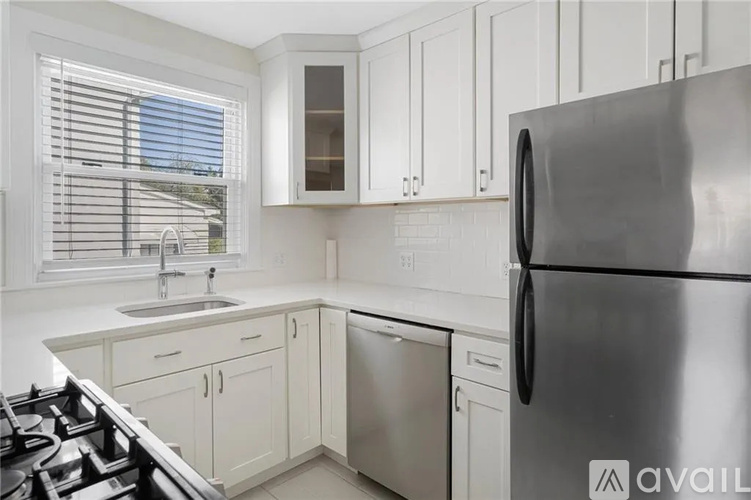 A modern kitchen with white cabinets and a stainless steel refrigerator.