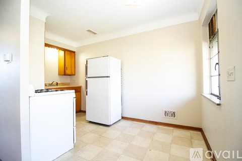 A kitchen with white appliances and a checkered floor.