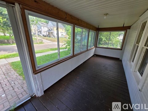 A sunroom with a view of the street and houses outside.