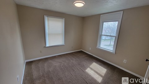 A room with two windows and carpeted floor.