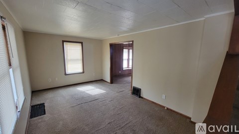 A room with a carpeted floor, a window, and a door.