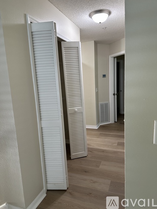 A hallway with a white door and a white wall.