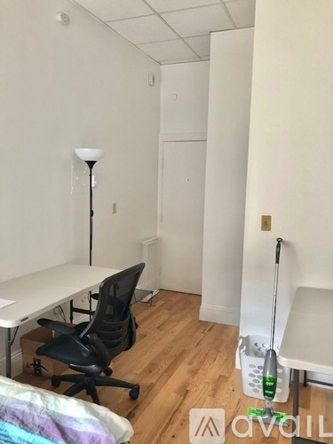 A room with a desk, chair, and a broom.