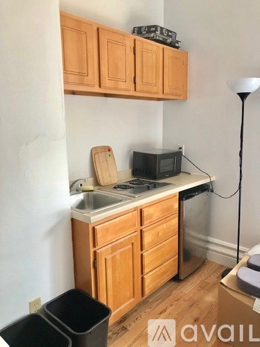 A kitchen with wooden cabinets and a black trash can.