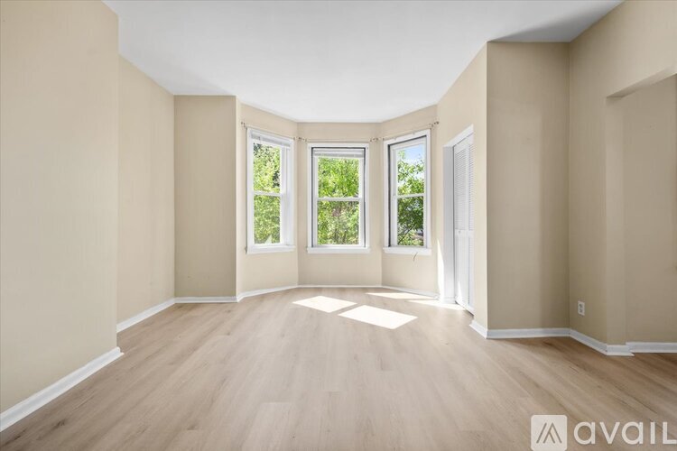 A spacious room with wooden flooring and large windows.