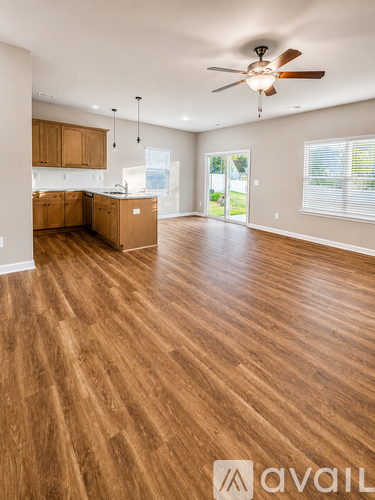 A spacious room with wooden floors and a ceiling fan.