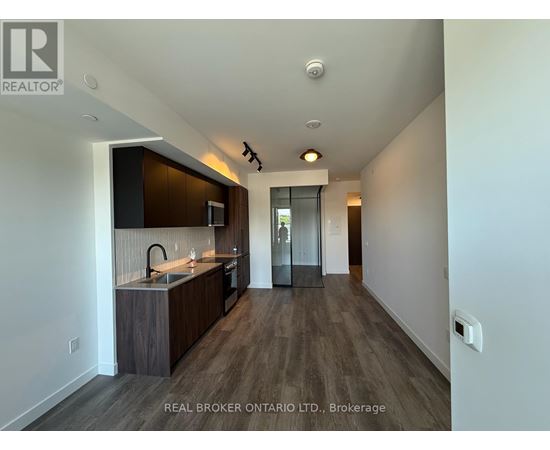 A modern kitchen with dark wood floors and white walls.