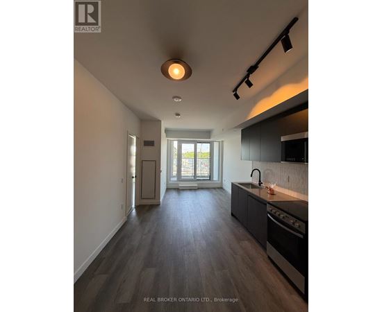A modern kitchen with dark wood floors and a large window.