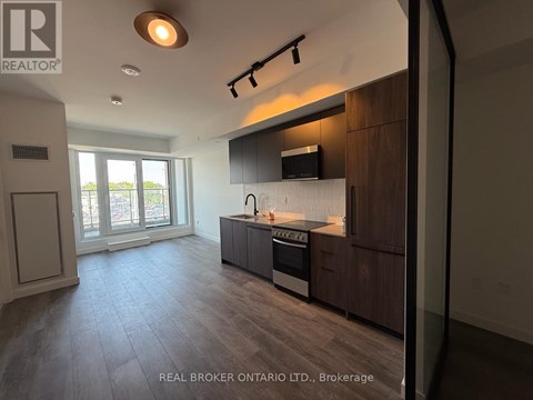 A modern kitchen with dark wood cabinets and a stainless steel stove top oven.
