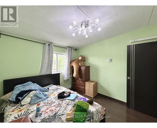 A bedroom with a bed, a teddy bear, and a chest of drawers.