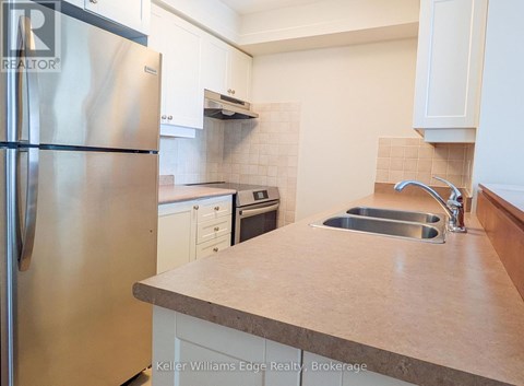 A kitchen with a stainless steel refrigerator and a sink.
