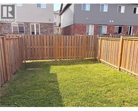 A backyard with a wooden fence and green grass.