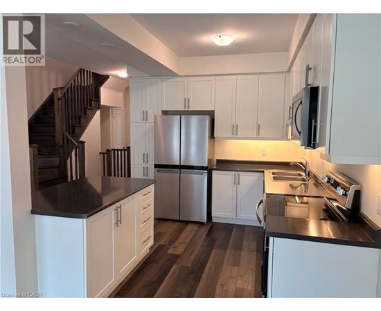 A kitchen with white cabinets and a stainless steel refrigerator.