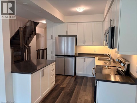 A kitchen with white cabinets and a stainless steel refrigerator.