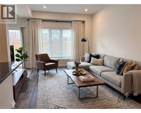 A well-lit living room with a grey sofa, a brown armchair, and a wooden coffee table.