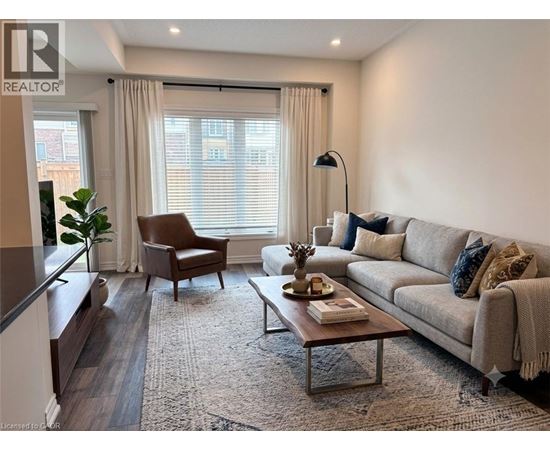 A well-lit living room with a grey sofa, a brown armchair, and a wooden coffee table.