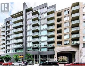 A tall residential building with balconies and a car dealership in front.