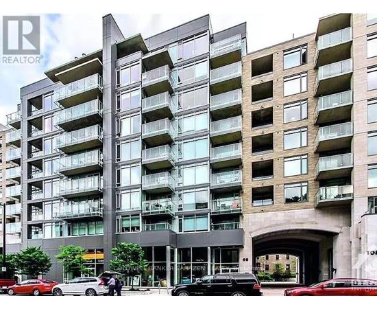 A tall residential building with balconies and a car dealership in front.