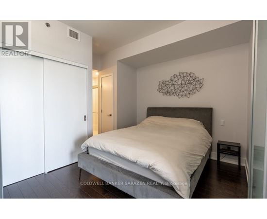 A bedroom with a bed, a wall hanging, and a small table.