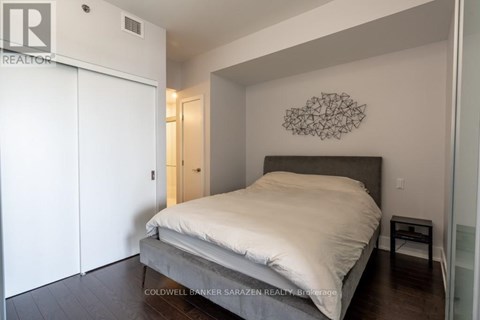 A bedroom with a bed, a wall hanging, and a small table.