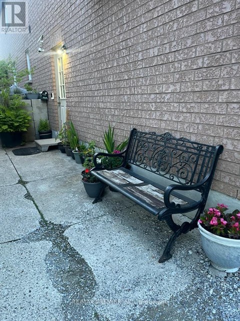 A black bench with a potted plant on the ground.