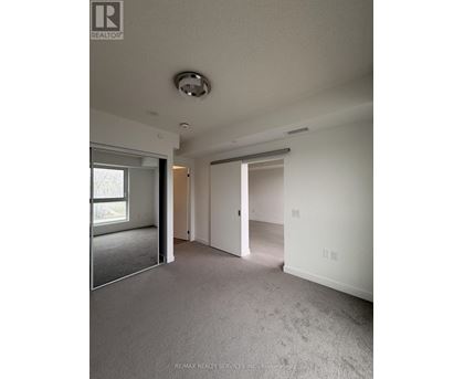 A spacious room with a carpeted floor and a ceiling light fixture.