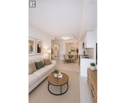A modern living room with a white couch, a coffee table, and a kitchen area in the background.