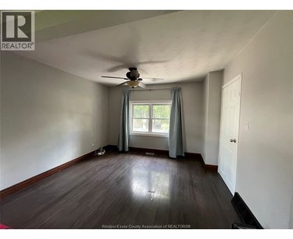 A room with a ceiling fan and a window with curtains.