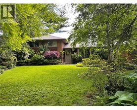 A house with a green lawn and trees in front.
