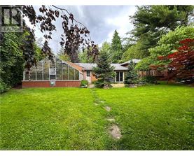 A green lawn with a path leading to a house and a greenhouse.