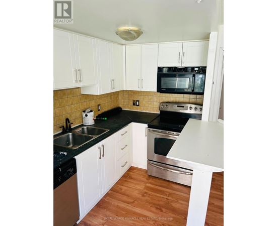 A kitchen with white cabinets and black countertops.
