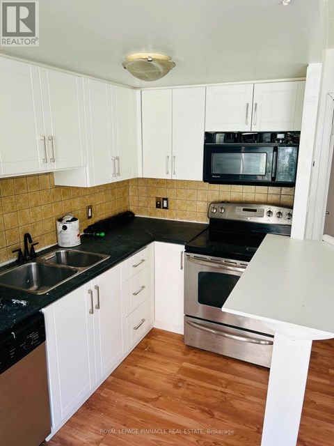 A kitchen with white cabinets and black countertops.