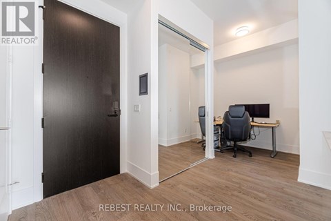 A room with a desk and a computer with a black chair.