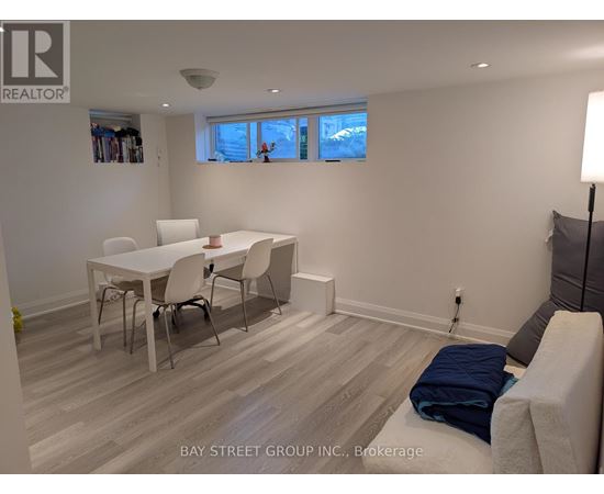 A white dining table with four chairs is in a room with a window.