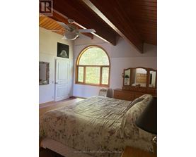 A bedroom with a large bed and a ceiling fan.