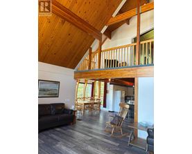 A living room with a couch, chairs, and a wooden ceiling.