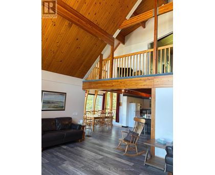 A living room with a couch, chairs, and a wooden ceiling.