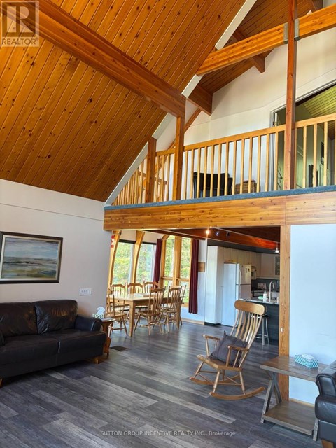 A living room with a couch, chairs, and a wooden ceiling.