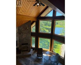 A living room with a stone fireplace and a view of a lake.