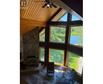 A living room with a stone fireplace and a view of a lake.